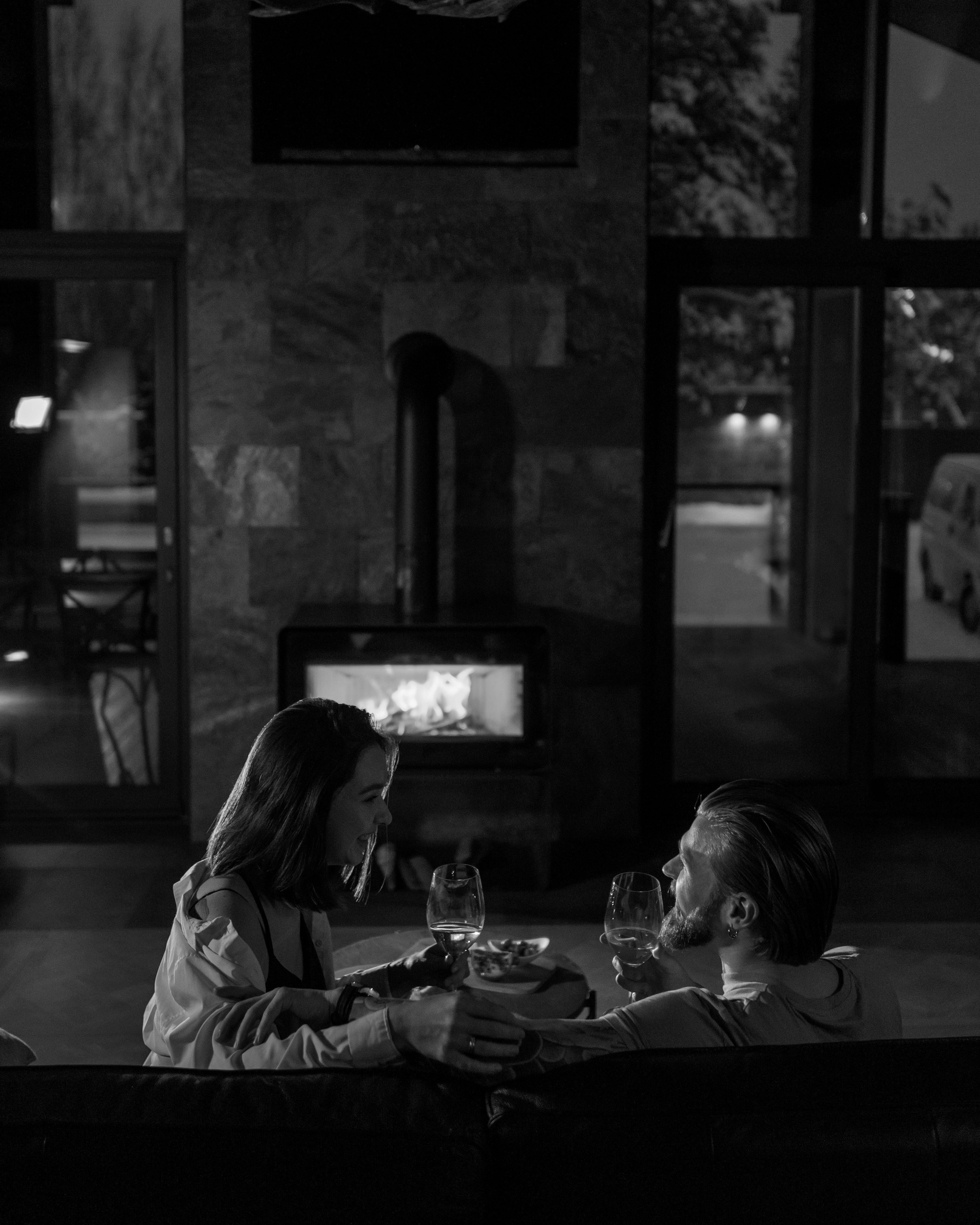 Two people sitting by a fireplace in a cozy indoor setting