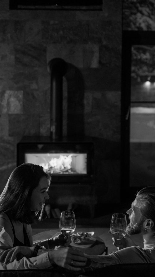 Two people sitting by a fireplace in a cozy indoor setting