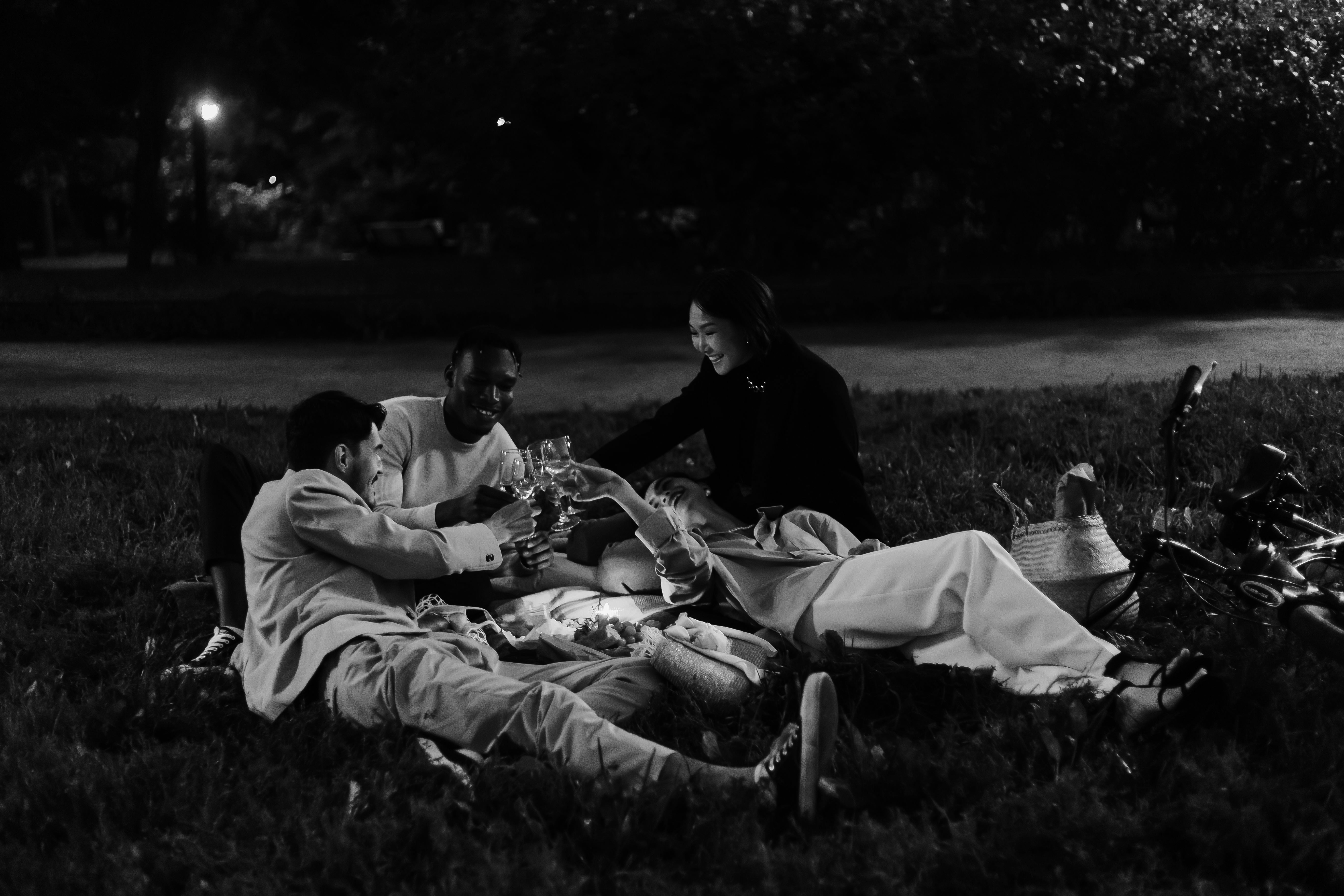 Three people having a picnic at night in a park