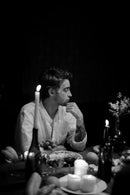 Man sitting at a table with candles and food, black and white photo