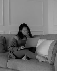 Woman using a laptop on a couch in a minimalistic room.